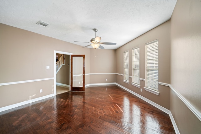 empty room featuring ceiling fan, a textured ceiling, visible vents, wood finished floors, and baseboards