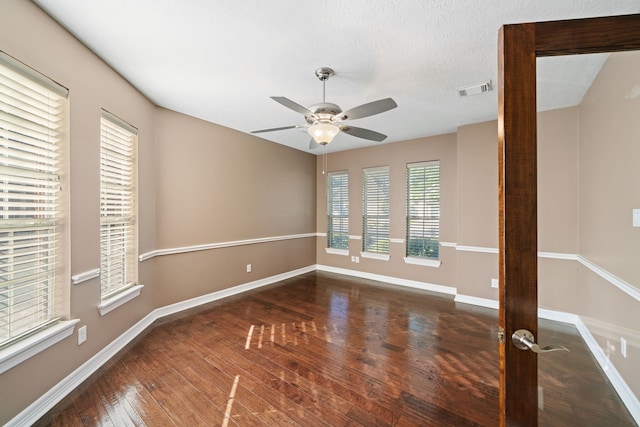 empty room with a ceiling fan, baseboards, visible vents, and hardwood / wood-style floors