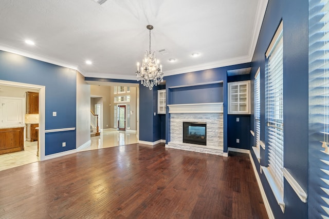 unfurnished living room featuring a stone fireplace, recessed lighting, wood finished floors, and a chandelier