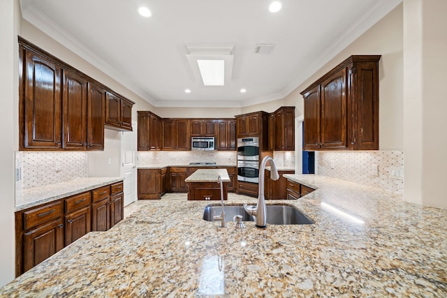 kitchen featuring stainless steel appliances, light stone counters, a sink, and dark brown cabinets