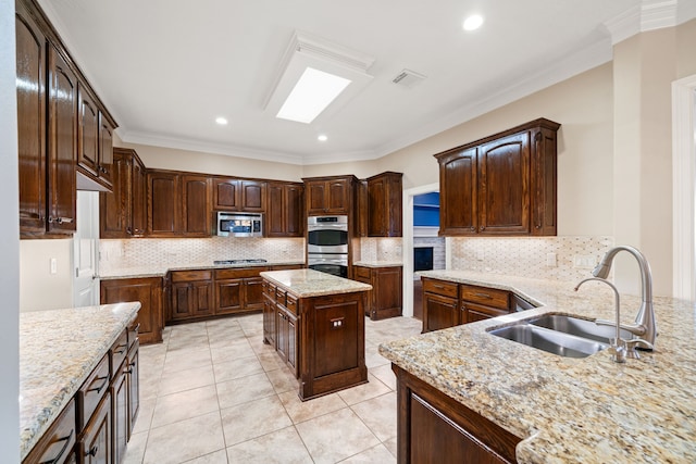 kitchen featuring visible vents, decorative backsplash, light stone countertops, a sink, and stainless steel appliances
