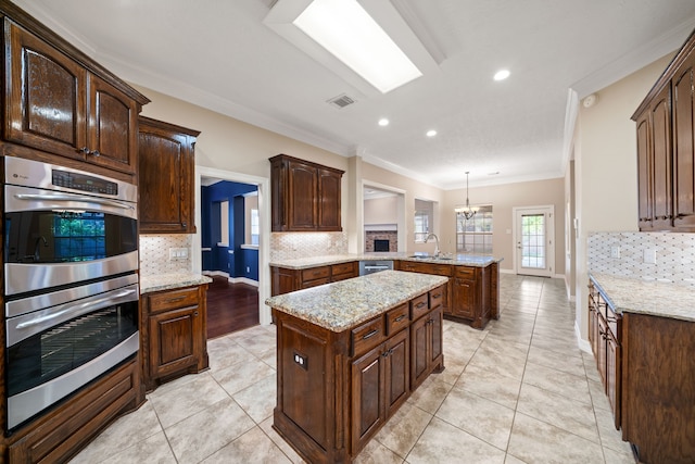 kitchen featuring stainless steel double oven, visible vents, tasteful backsplash, a sink, and a peninsula