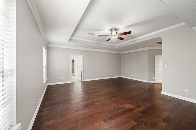 empty room with a ceiling fan, visible vents, dark wood finished floors, a raised ceiling, and baseboards