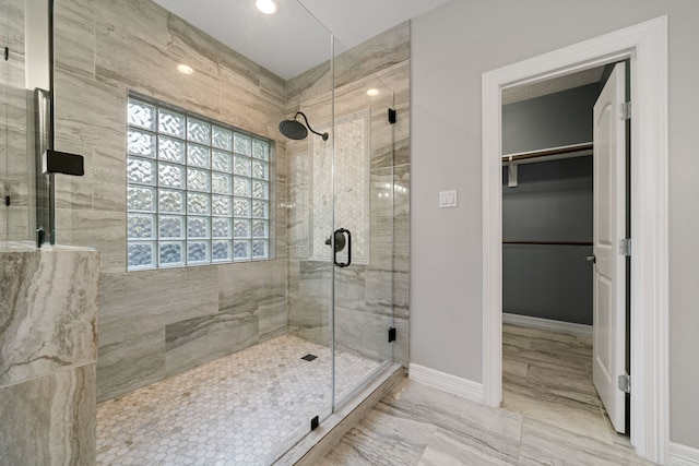 bathroom featuring a walk in closet, a shower stall, baseboards, marble finish floor, and recessed lighting