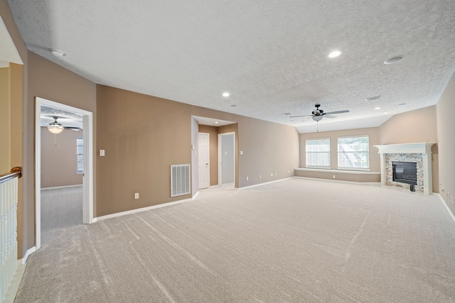 unfurnished living room with visible vents, a glass covered fireplace, ceiling fan, and light carpet