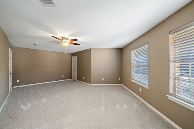 unfurnished room with a ceiling fan, a textured ceiling, visible vents, baseboards, and light carpet