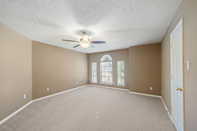 carpeted empty room with baseboards, a ceiling fan, and a textured ceiling