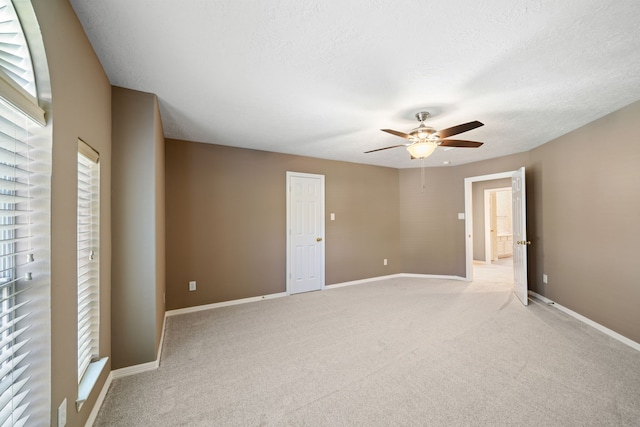spare room with light colored carpet, a ceiling fan, a textured ceiling, and a healthy amount of sunlight
