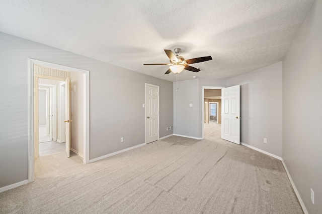 unfurnished bedroom with baseboards, a ceiling fan, a textured ceiling, and light carpet