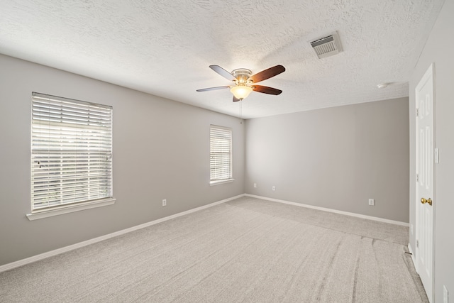 empty room with ceiling fan, light colored carpet, a textured ceiling, and visible vents