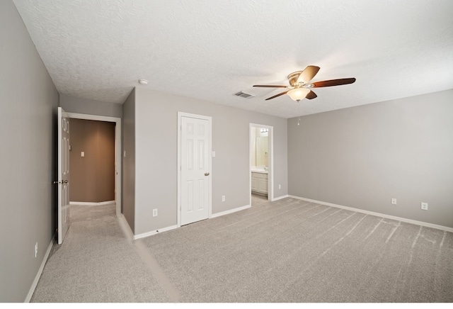unfurnished bedroom with visible vents, light carpet, baseboards, connected bathroom, and a textured ceiling