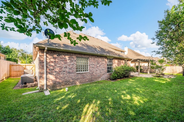 rear view of property with a lawn, a shingled roof, cooling unit, and a fenced backyard