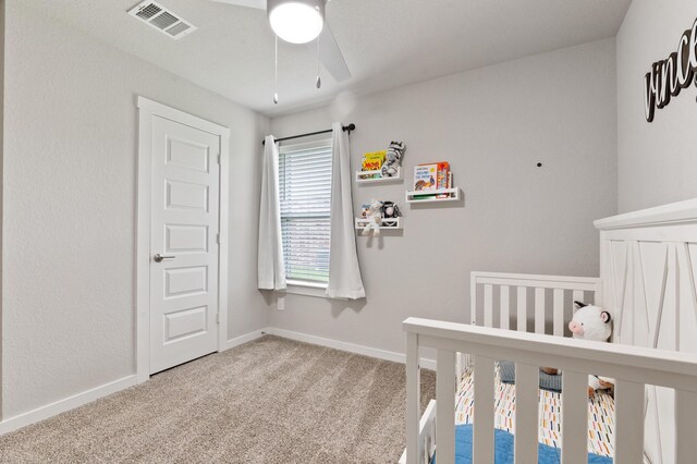 bedroom with ceiling fan, a crib, carpet, baseboards, and visible vents