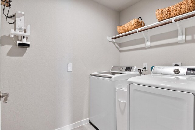 washroom featuring laundry area, baseboards, and washer and dryer