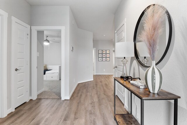 corridor with baseboards and light wood-style floors