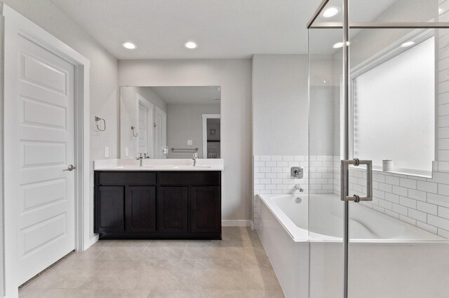 full bathroom featuring a garden tub, a sink, double vanity, and recessed lighting