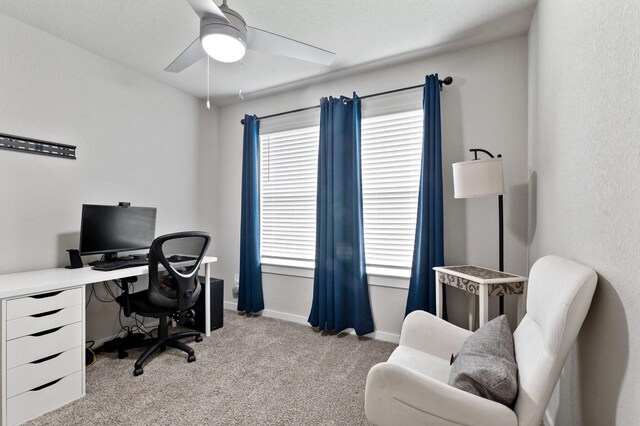 home office with baseboards, a ceiling fan, and light colored carpet