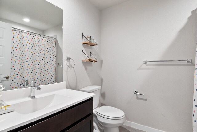 full bathroom with vanity, baseboards, a shower with shower curtain, and toilet