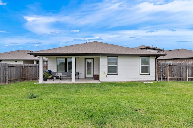 back of house featuring a fenced backyard, a yard, a patio area, and roof with shingles