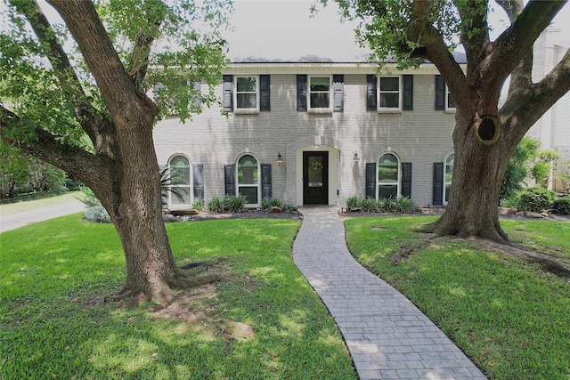 colonial-style house with brick siding and a front yard