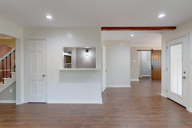 empty room with a barn door, stairs, baseboards, wood finished floors, and ornamental molding