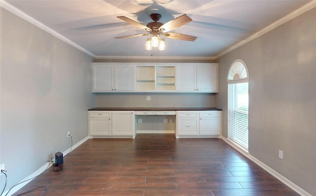 kitchen with dark wood-style flooring, dark countertops, ceiling fan, built in desk, and ornamental molding