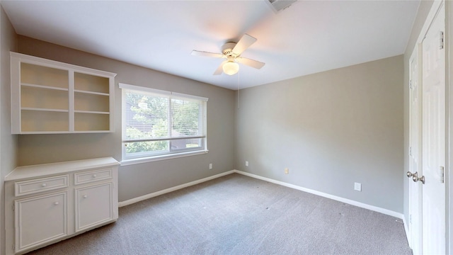interior space featuring baseboards, ceiling fan, light carpet, and visible vents