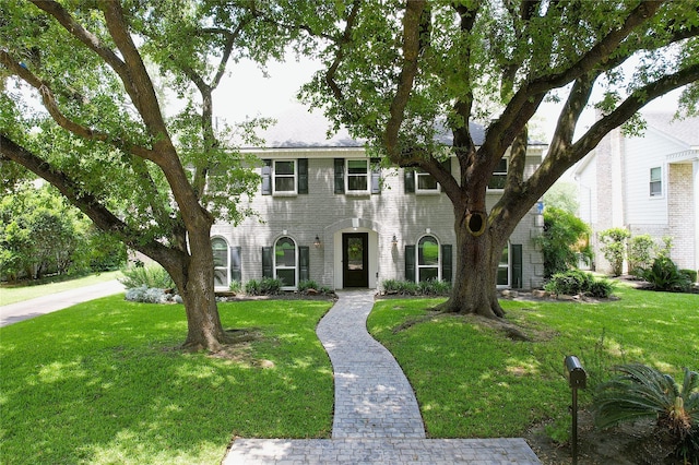 colonial house featuring brick siding and a front lawn
