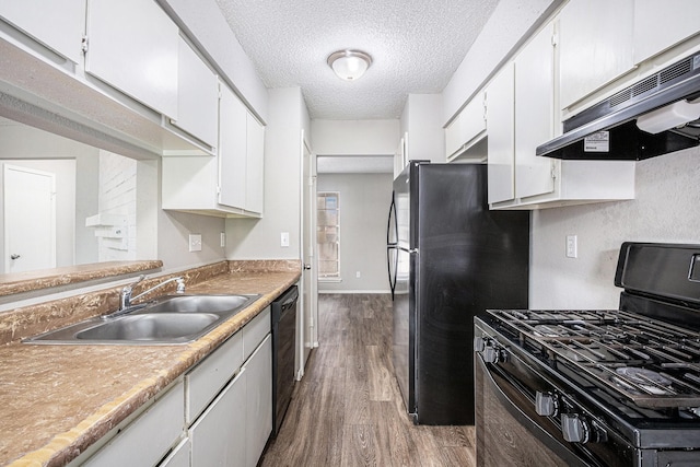 12719 Panay Dr, Houston, TX 77048 - kitchen with under cabinet range hood, white cabinets, a sink, dark wood finished floors, and black appliances
