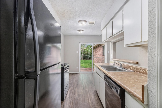 12719 Panay Dr, Houston, TX 77048 - kitchen featuring visible vents, wood finished floors, white cabinetry, a sink, and stainless steel appliances