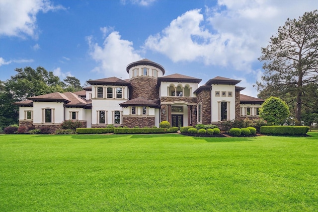mediterranean / spanish-style house featuring a front lawn, stucco siding, and stone siding