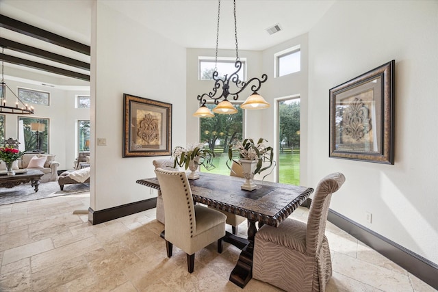 dining room featuring baseboards, visible vents, stone tile floors, and a chandelier