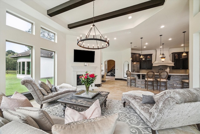 living room with an inviting chandelier, beam ceiling, a fireplace, recessed lighting, and arched walkways