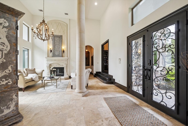 entrance foyer featuring a high ceiling, a premium fireplace, arched walkways, baseboards, and stone tile flooring