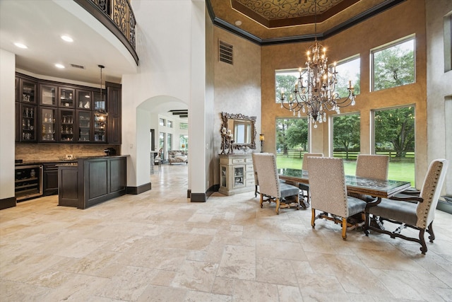 dining space with visible vents, a towering ceiling, arched walkways, wine cooler, and stone tile floors