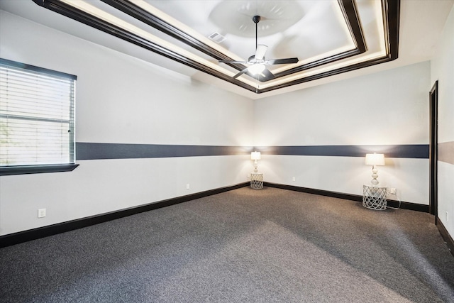 empty room featuring carpet flooring, ceiling fan, a raised ceiling, baseboards, and visible vents