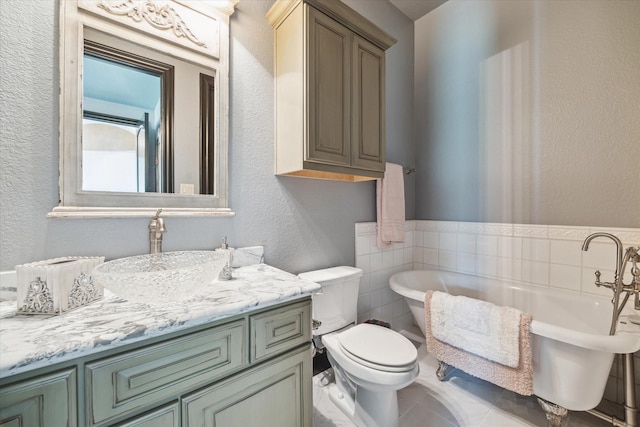full bathroom with vanity, a textured wall, toilet, tile walls, and a freestanding bath
