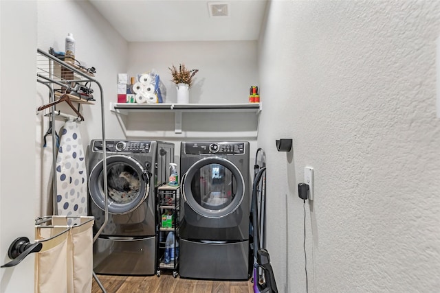 laundry area with laundry area, independent washer and dryer, visible vents, wood finished floors, and a textured wall