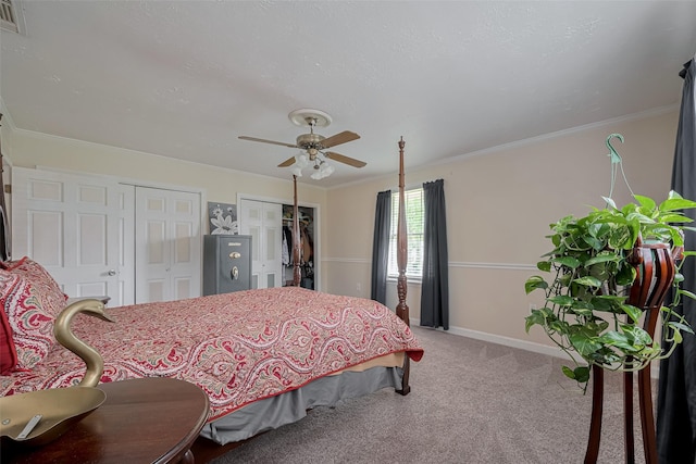 bedroom with ceiling fan, baseboards, carpet floors, multiple closets, and ornamental molding