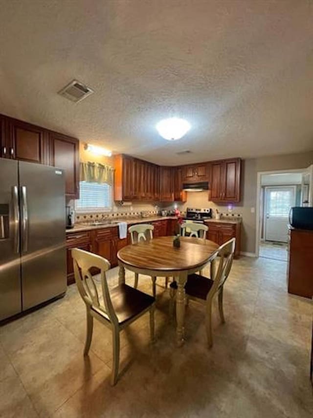 dining area with plenty of natural light, a textured ceiling, and visible vents