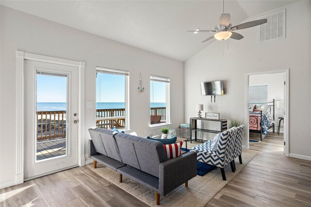 living area with visible vents, wood finished floors, ceiling fan, high vaulted ceiling, and a water view