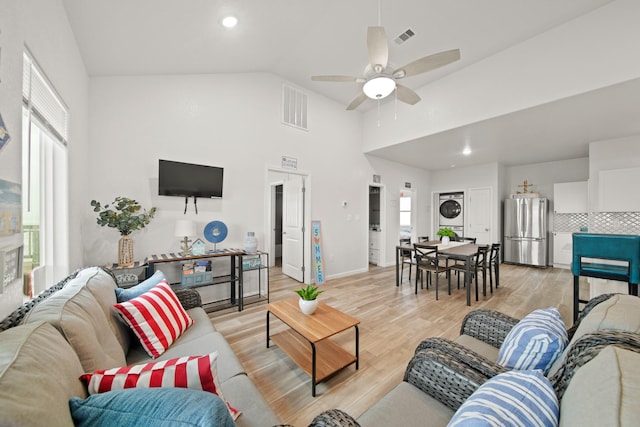 living area with a healthy amount of sunlight, ceiling fan, stacked washer / drying machine, and visible vents