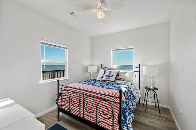 bedroom featuring baseboards, multiple windows, wood finished floors, and visible vents