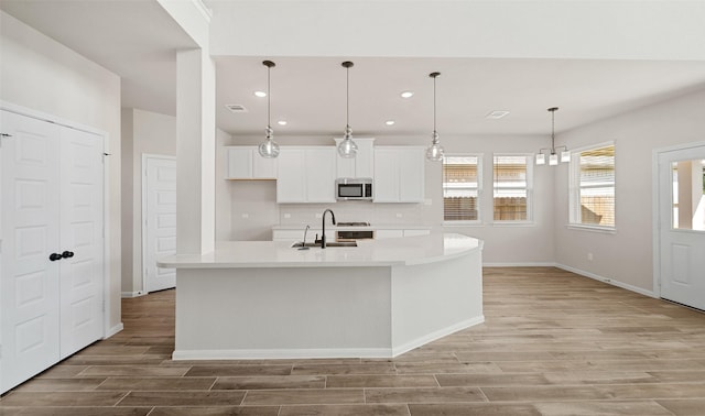 2617 Bisbee Rd, League City, TX 77573 - kitchen featuring stainless steel microwave, recessed lighting, a sink, light countertops, and light wood finished floors