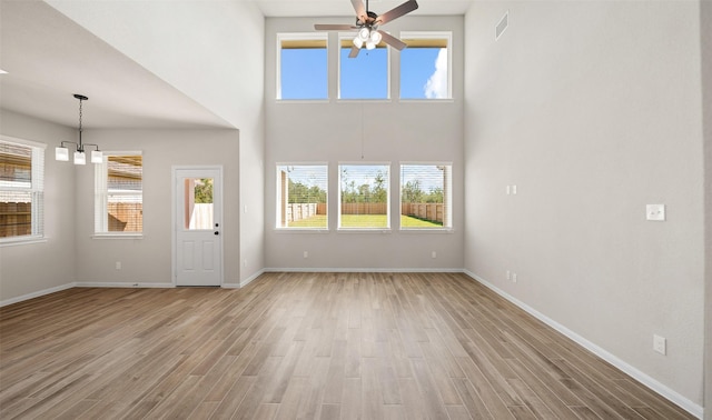 2617 Bisbee Rd, League City, TX 77573 - unfurnished living room featuring a ceiling fan, a chandelier, light wood-style floors, plenty of natural light, and a towering ceiling