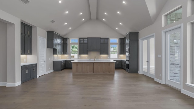 12944 Whitewater Way, Conroe, TX 77302 - kitchen featuring high vaulted ceiling, beamed ceiling, an island with sink, wood finished floors, and light countertops