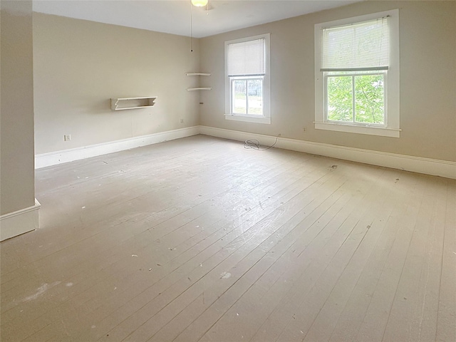 spare room featuring baseboards, a wealth of natural light, and hardwood / wood-style flooring