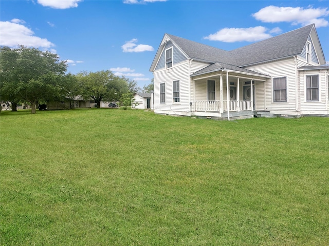 back of property featuring roof with shingles, a yard, and covered porch