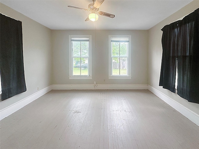 empty room with baseboards, a ceiling fan, and light wood-style floors