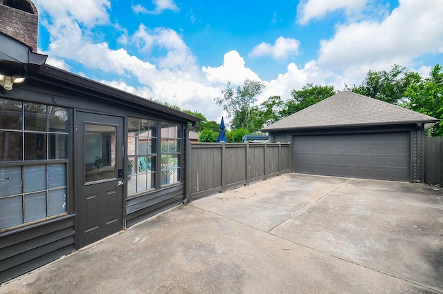 view of patio / terrace featuring fence, an outbuilding, and a garage